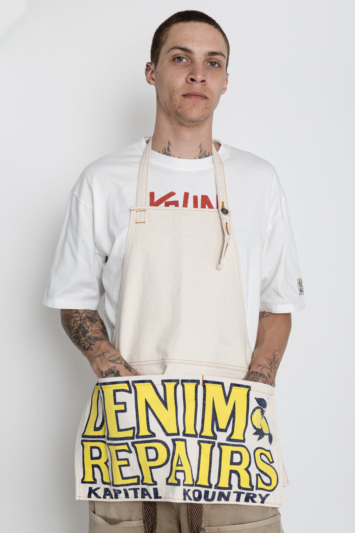 Kapital 2023 Spring Summer advertising apron with a vintage-like logo 3 pockets with different sizes. Featured on the apron is yellow Novelty typography. 13oz distressed denim. Color: Ecru 100% Cotton Made in Japan. 