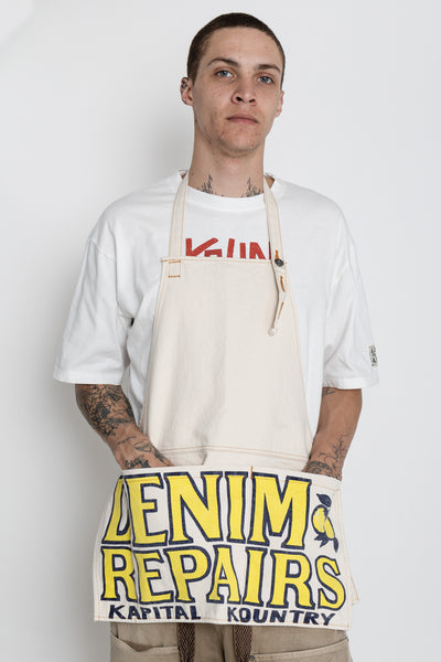 Kapital 2023 Spring Summer advertising apron with a vintage-like logo 3 pockets with different sizes. Featured on the apron is yellow Novelty typography. 13oz distressed denim. Color: Ecru 100% Cotton Made in Japan. 