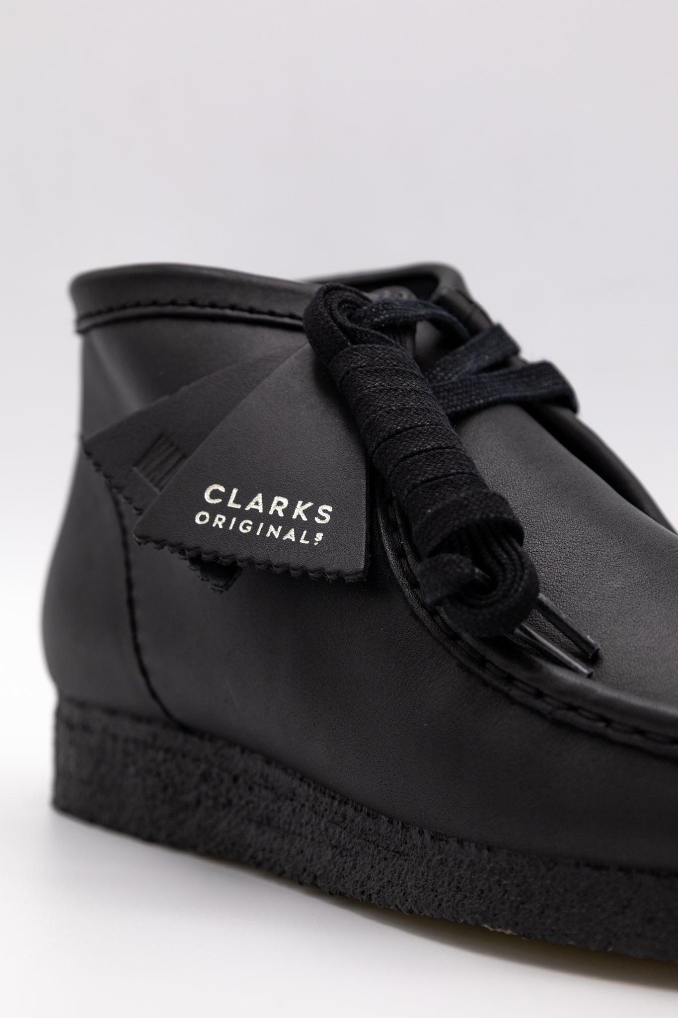 Clark's Original Wallaby Boot in Black Leather. With rugged leather uppers for a premium feel, this silhouette sits atop a chunky pebble crepe sole to stay true to its design DNA, while waxy laces and tonal fobs complete this stone cold classic. Premium black leather upper Natural rubber pebble crepe sole Finished with two Clarks Originals fobs