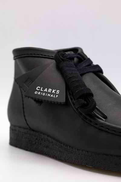 Clark's Original Wallaby Boot in Black Leather. With rugged leather uppers for a premium feel, this silhouette sits atop a chunky pebble crepe sole to stay true to its design DNA, while waxy laces and tonal fobs complete this stone cold classic. Premium black leather upper Natural rubber pebble crepe sole Finished with two Clarks Originals fobs