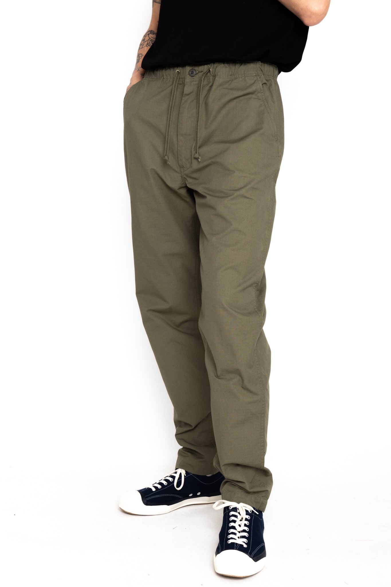 Easy to wear Orslow trousers with an elastic waist and cord drawstring made in Japanese 100% cotton ripstop fabric. Straight leg with a slight taper that features two front pockets and one back. Color: Army Green. Fabric: 100% Cotton. Unisex. Made in Japan.