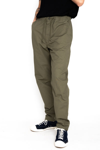 Easy to wear Orslow trousers with an elastic waist and cord drawstring made in Japanese 100% cotton ripstop fabric. Straight leg with a slight taper that features two front pockets and one back. Color: Army Green. Fabric: 100% Cotton. Unisex. Made in Japan.