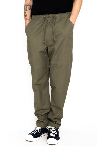 Easy to wear Orslow trousers with an elastic waist and cord drawstring made in Japanese 100% cotton ripstop fabric. Straight leg with a slight taper that features two front pockets and one back. Color: Army Green. Fabric: 100% Cotton. Unisex. Made in Japan.