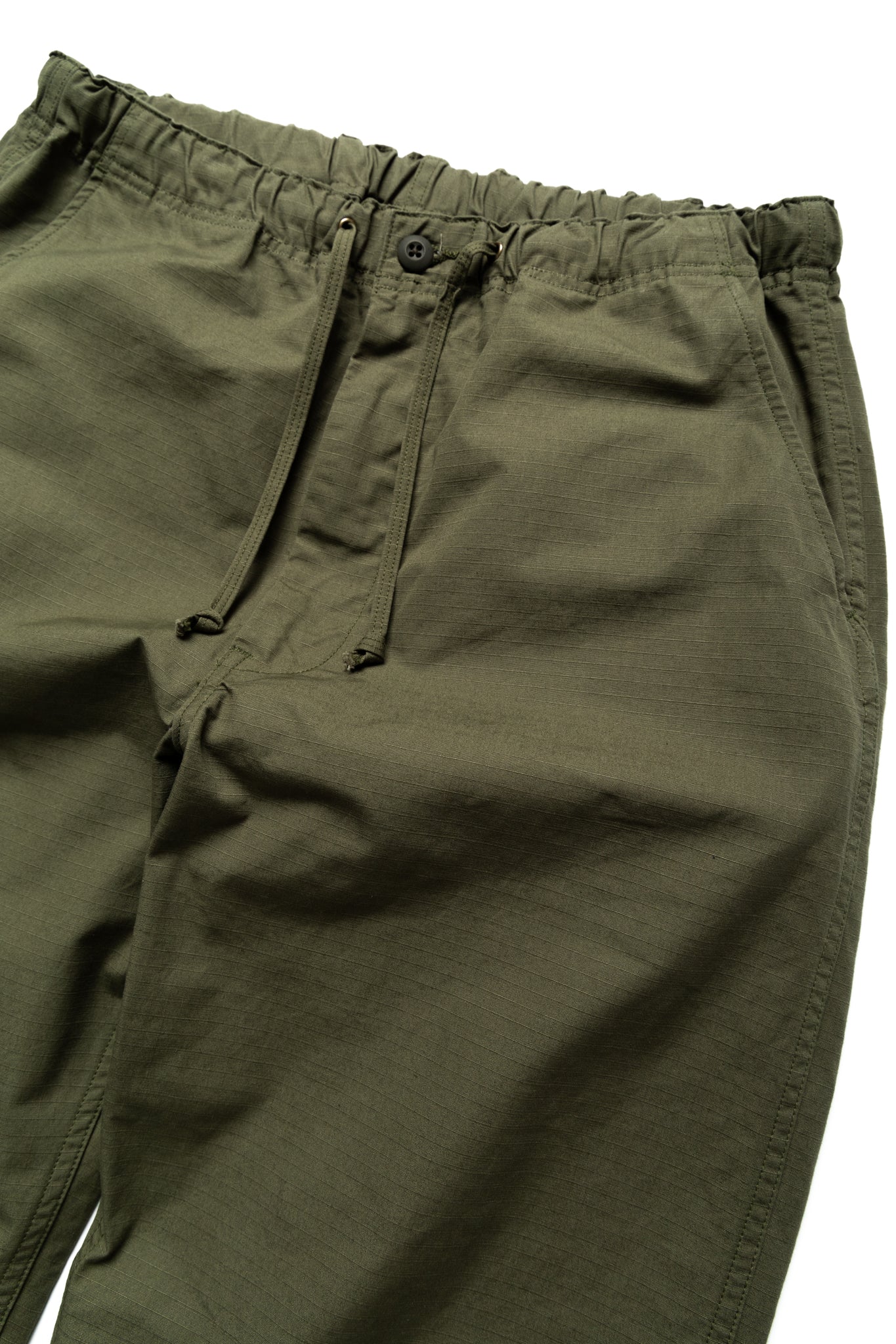 Easy to wear Orslow trousers with an elastic waist and cord drawstring made in Japanese 100% cotton ripstop fabric. Straight leg with a slight taper that features two front pockets and one back. Color: Army Green. Fabric: 100% Cotton. Unisex. Made in Japan.