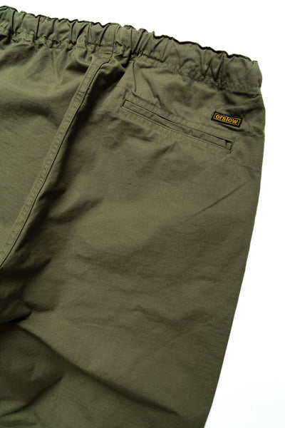 Easy to wear Orslow trousers with an elastic waist and cord drawstring made in Japanese 100% cotton ripstop fabric. Straight leg with a slight taper that features two front pockets and one back. Color: Army Green. Fabric: 100% Cotton. Unisex. Made in Japan.