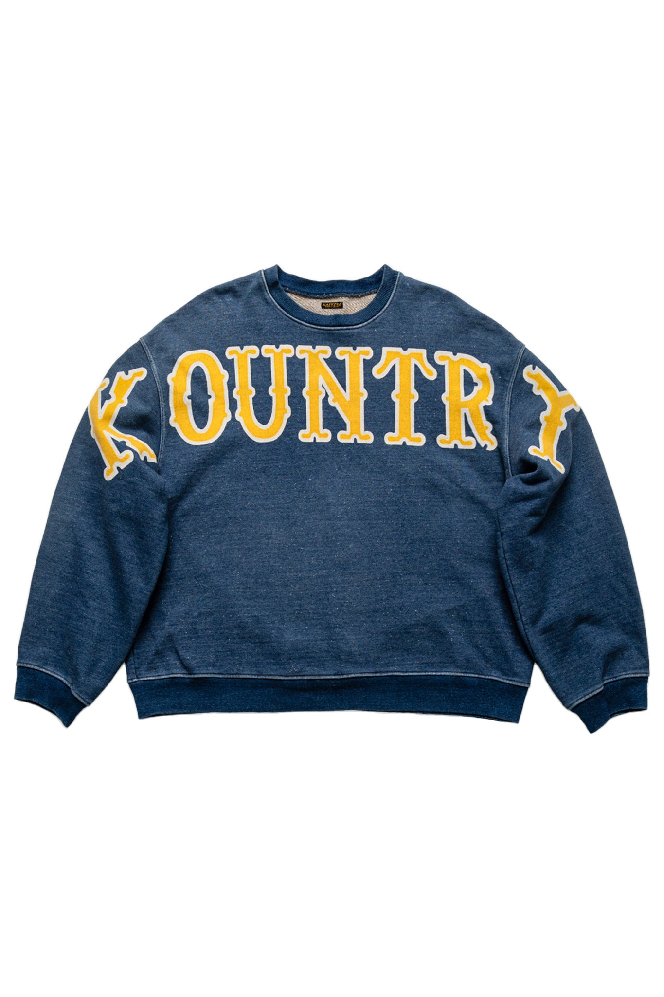 Kapital long sleeve sweatshirt pullover that is an indigo fleece loose fit. Loose fit. Across the front is a large graphic text of the KOUNTRY logo. The back has a T-shaped split back and a cinch back. Color: Indigo 100% Cotton. Made In Japan. Unisex. 